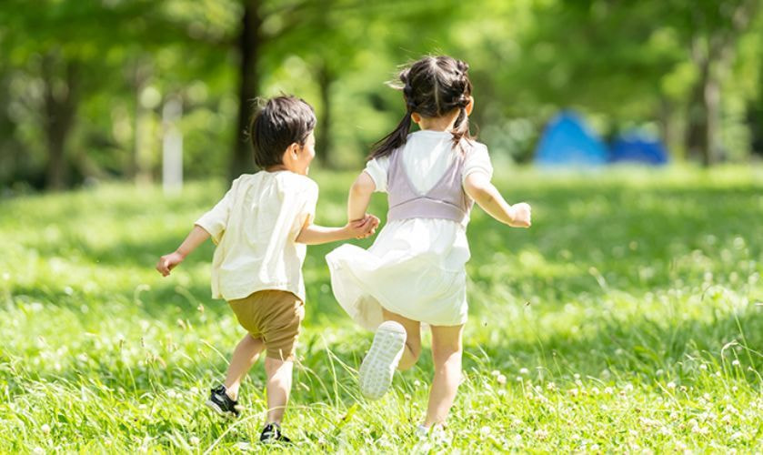 公園を走る二人の子供の後ろ姿