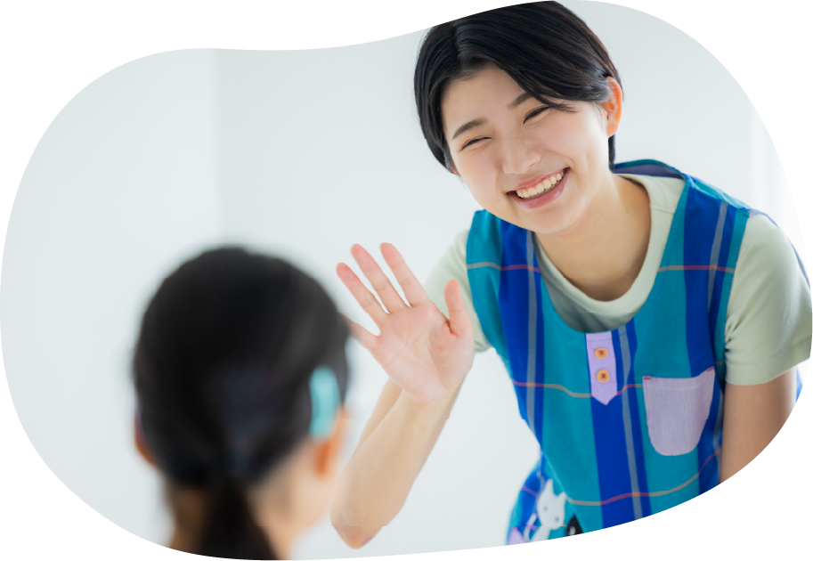 子供に笑顔で手を振る保育士